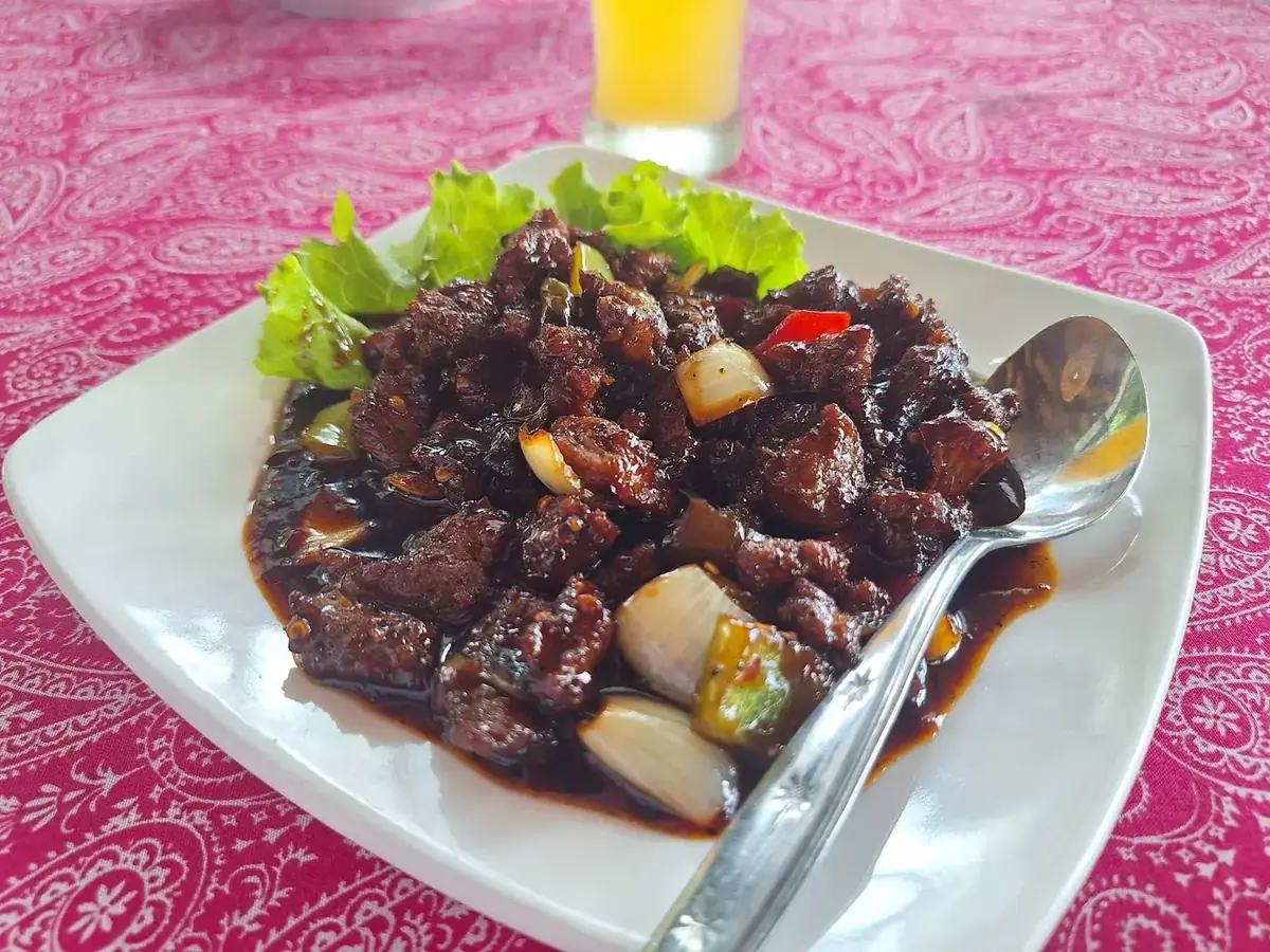 Sepiring ayam berbumbu manis pedas di atas taplak merah muda