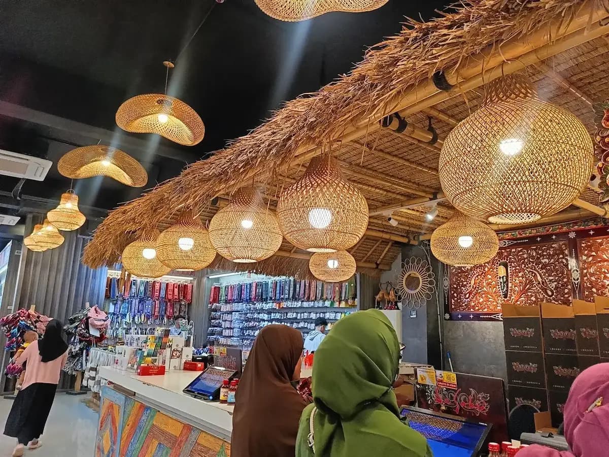 Lorong toko penuh pengunjung di bawah deretan lampu rotan